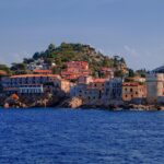 Vista panoramica del villaggio corso immerso tra mare cristallino e montagne verdi.